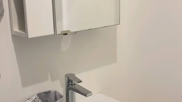 Lavabo blanc encastré avec mitigeur chromé et miroir mural, dans une salle d’eau aux murs clairs